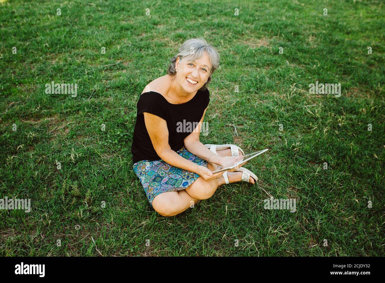 Femme âgée discutant en ligne avec sa tablette dans un parc Banque D'Images
