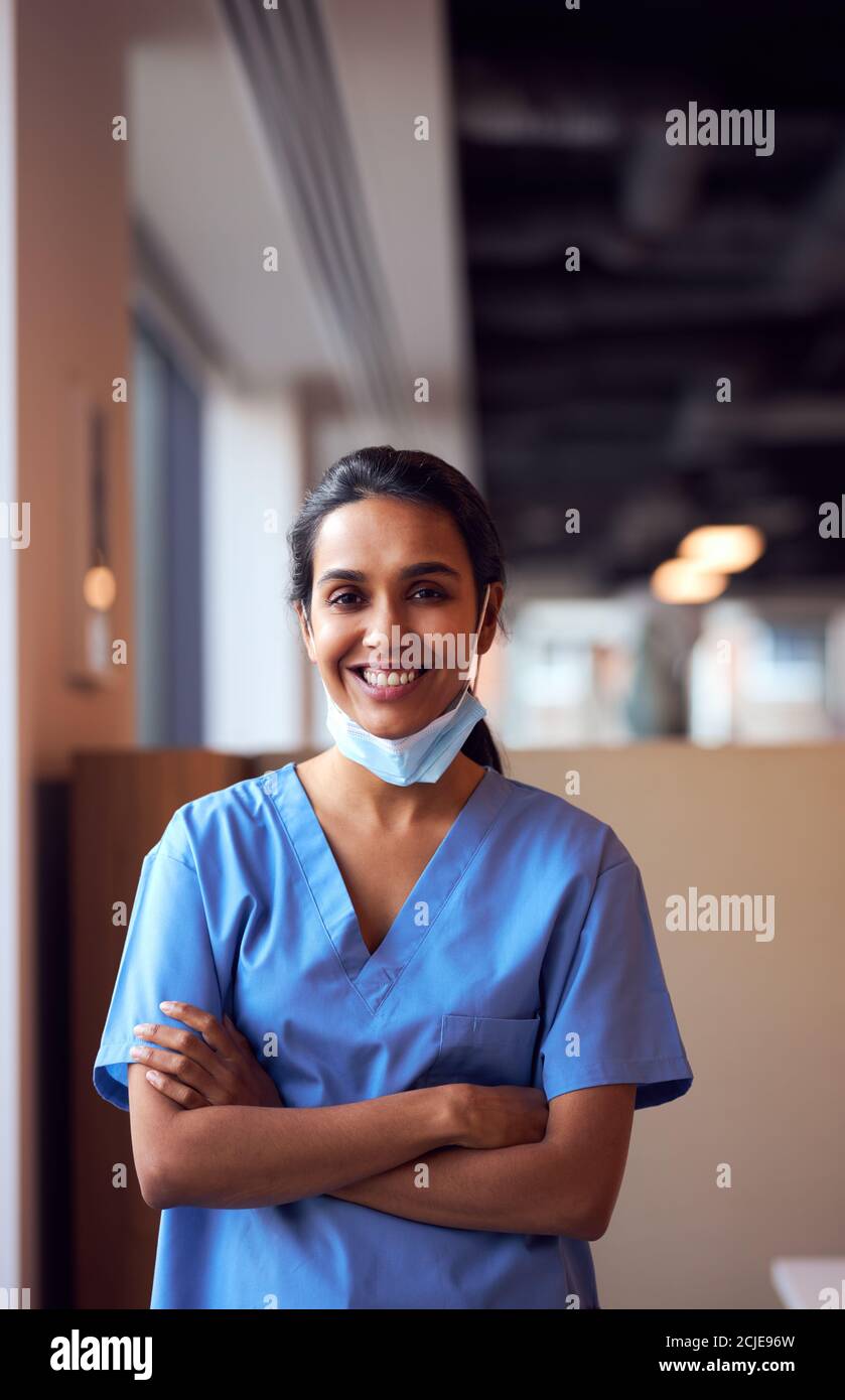 Femme souriante médecin avec masque de visage portant des exfoliants dans occupé Hôpital pendant une pandémie de santé Banque D'Images