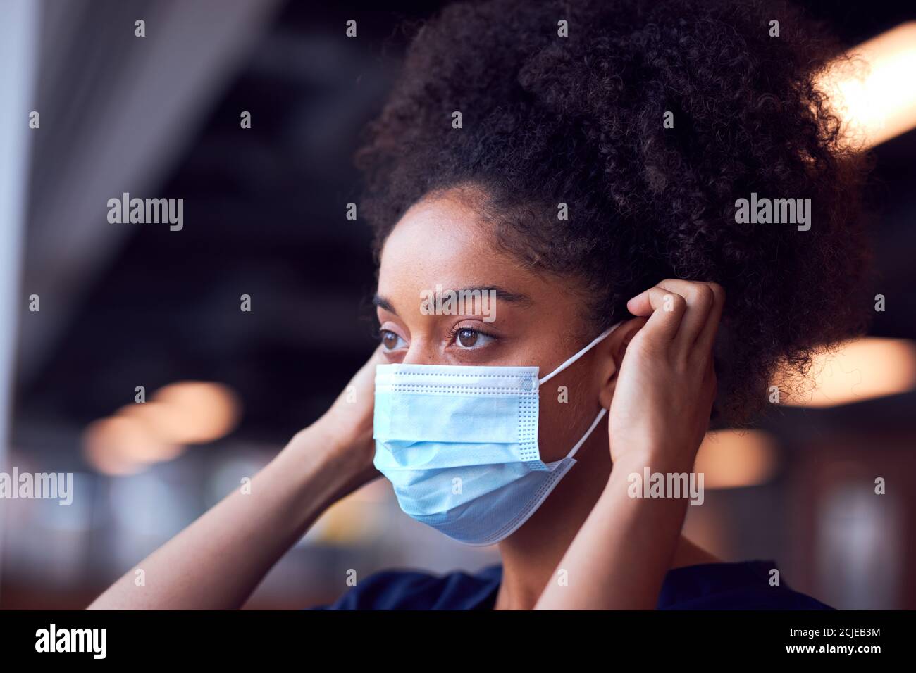 Femme Docteur en gommages mettant sur le masque de visage sous pression Dans l'hôpital occupé pendant la pandémie de santé Banque D'Images