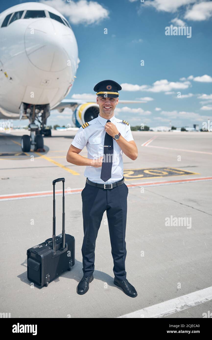 Un beau pilote homme qui règle sa cravate à l'aéroport Photo Stock - Alamy