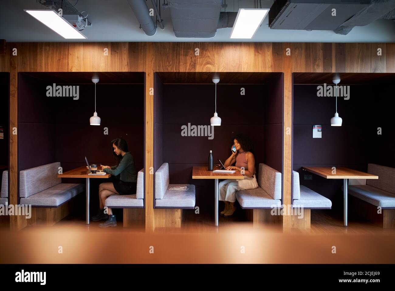 Femmes d'affaires travaillant dans des cabines socialement distancées dans le bureau moderne pendant Pandémie de santé Banque D'Images