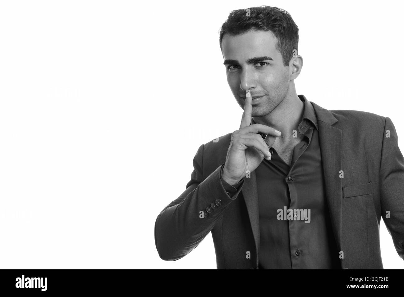 Jeune homme d'affaires iranien beau avec le doigt sur les lèvres Banque D'Images