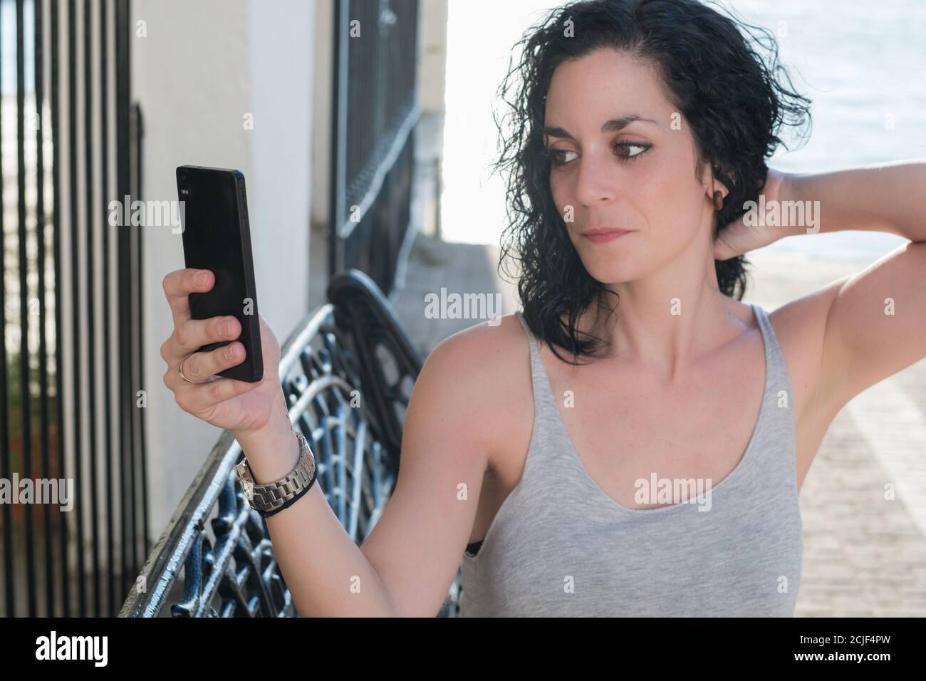 jeune fille aux cheveux bouclés souriant en faisant un appel vidéo avec son téléphone portable Banque D'Images