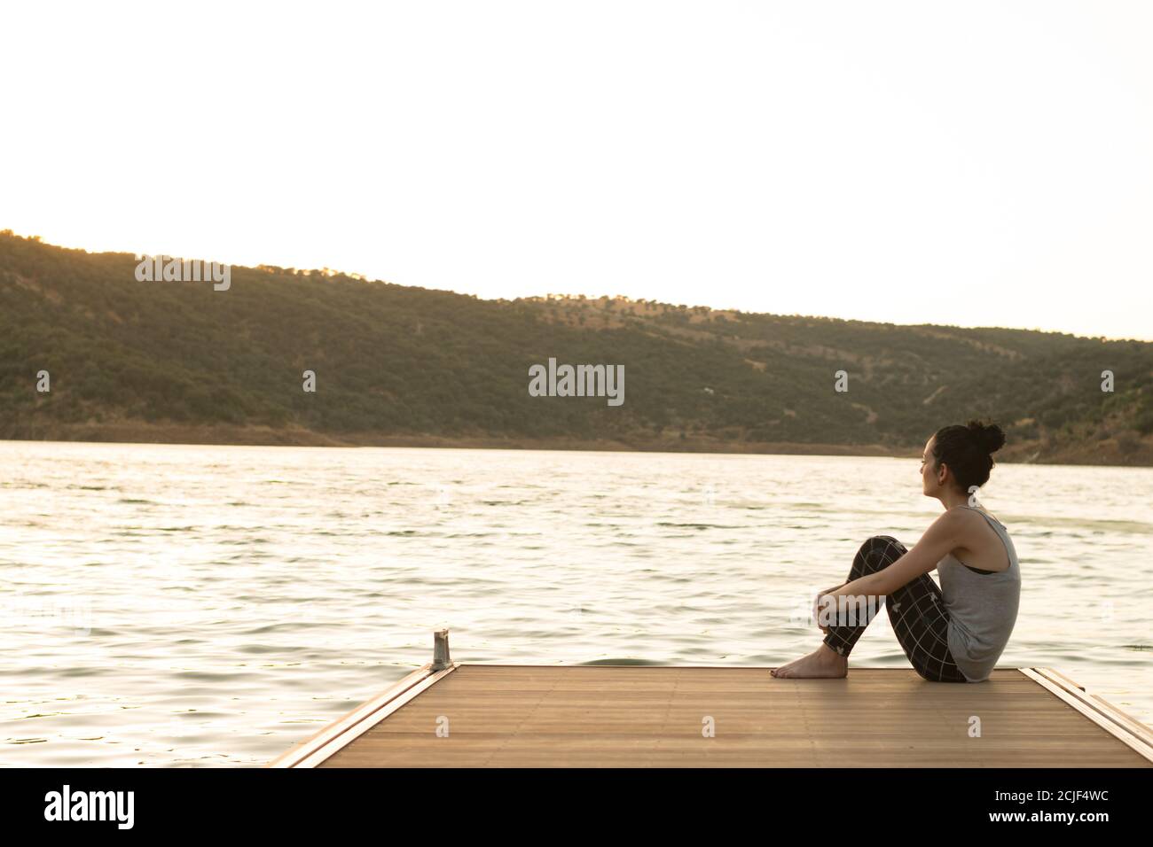 Femme assise sur une jetée en bois sur le lac Banque D'Images