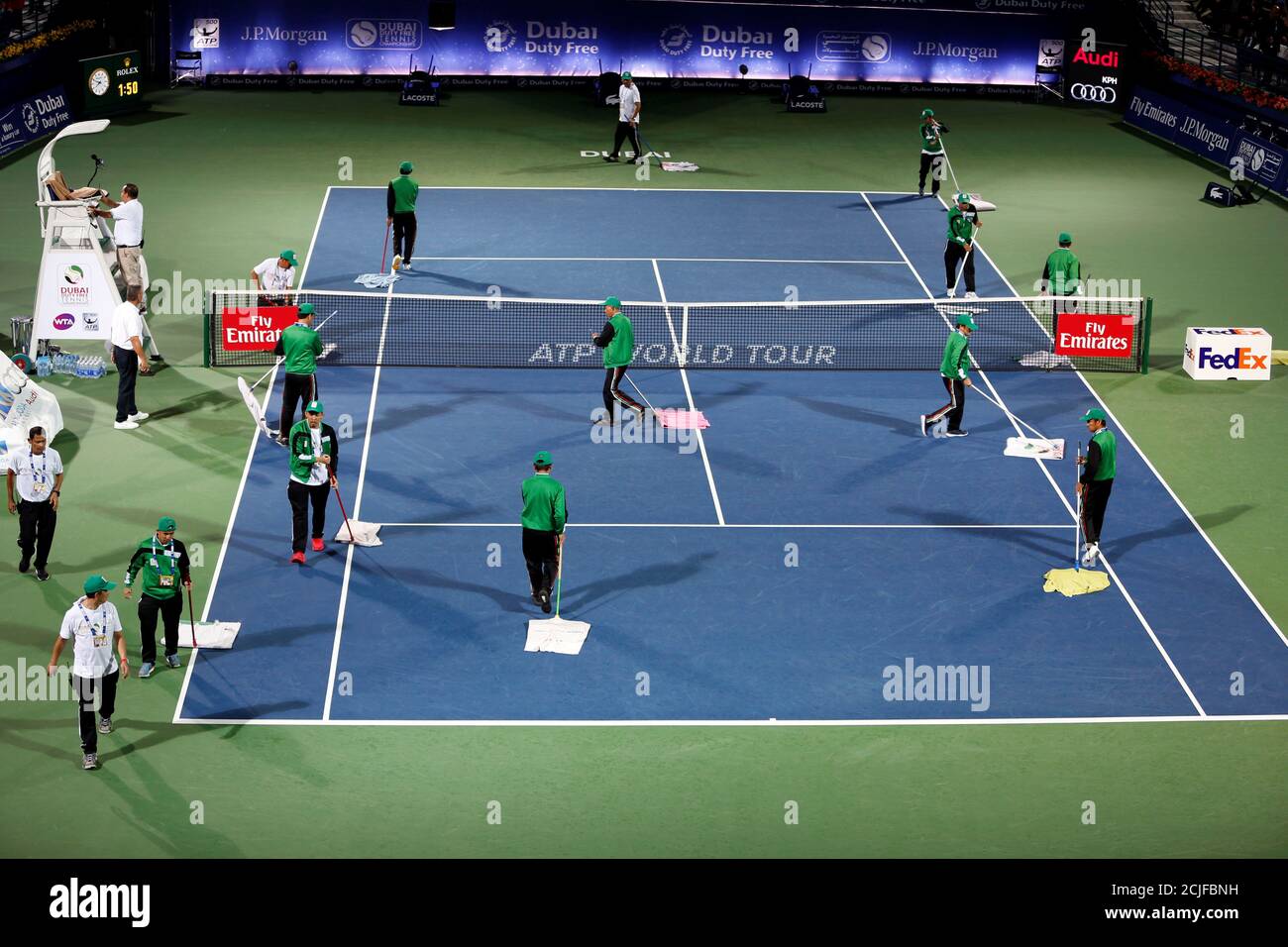 Tennis - ATP - Dubai Open - semifinal - Dubai, Émirats Arabes Unis - 2 mars  2018. Des volontaires nettoient le terrain après la pluie lors d'un match  semi-final entre Filip Krajinovic