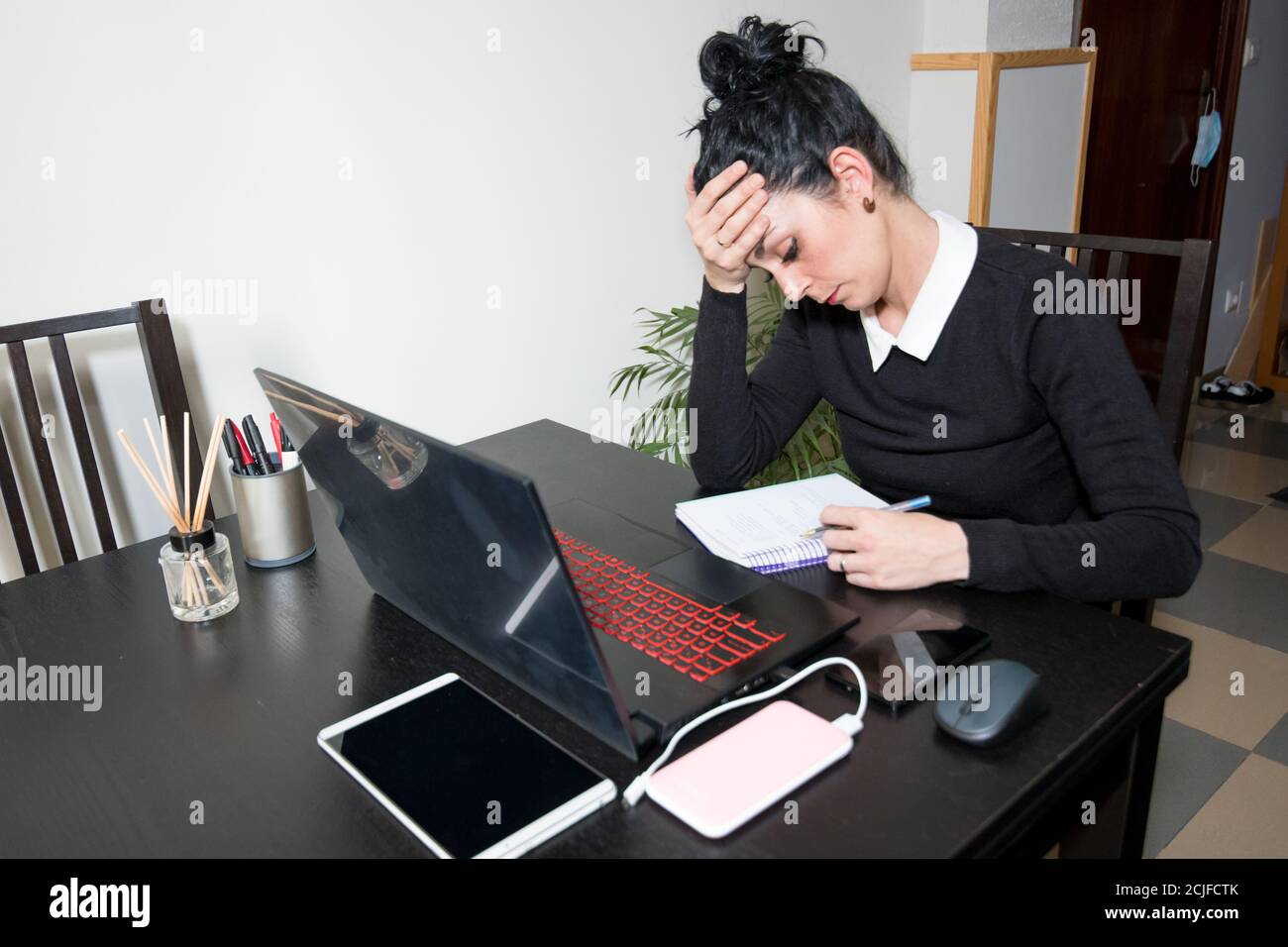 une jeune fille a stressé en travaillant à la maison avec un ordinateur portable et une tablette. Banque D'Images