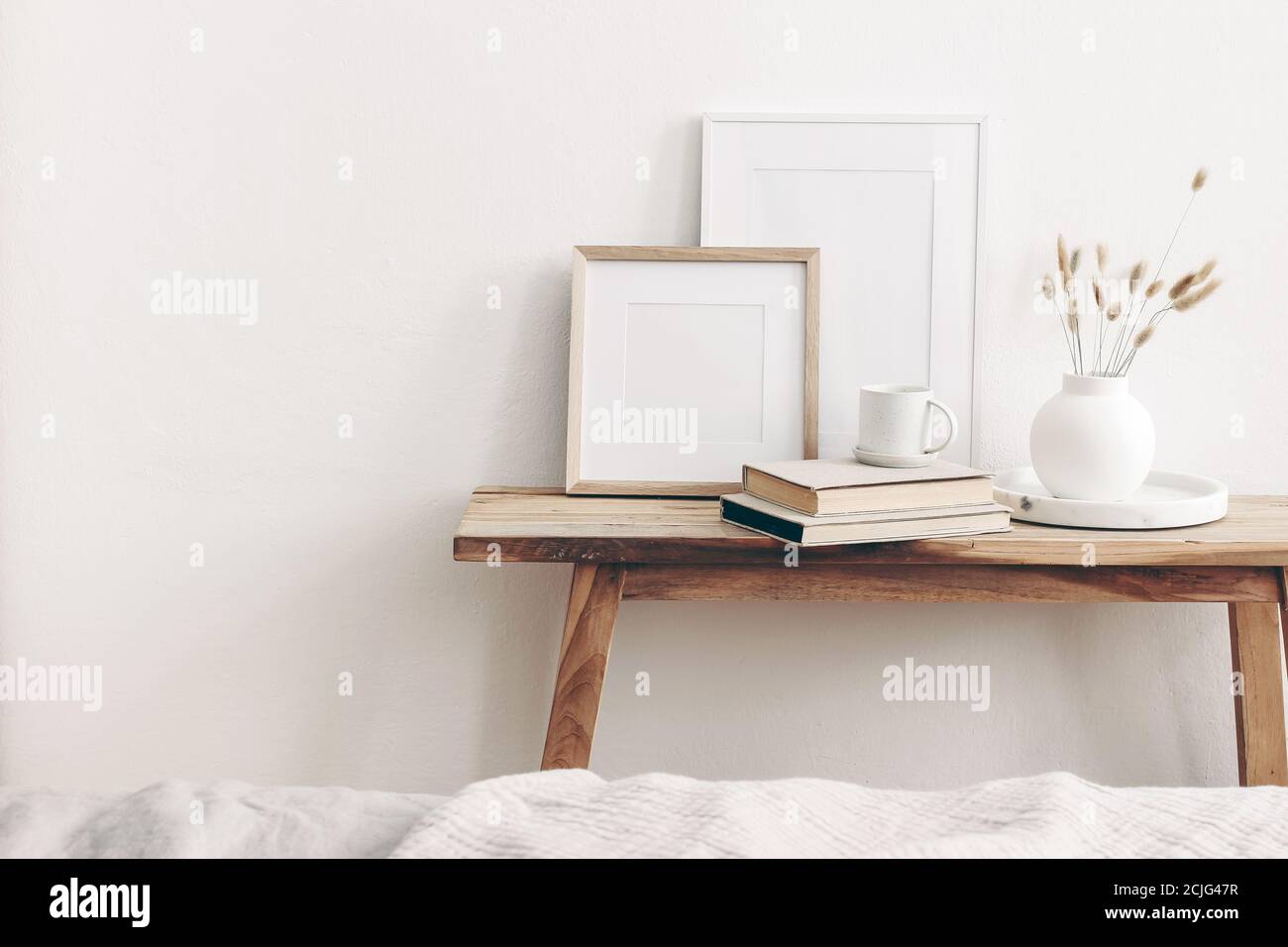 Maquettes de cadres en bois carrés et portrait. Banc vintage, table avec vase moderne en céramique, queue de lapin, herbe sèche, livres et tasse de café. Blanc Banque D'Images
