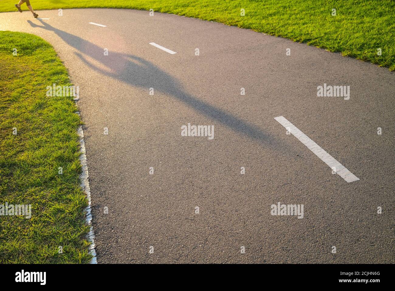 Jambes et ombre d'une personne qui court sur un jogging piste Banque D'Images