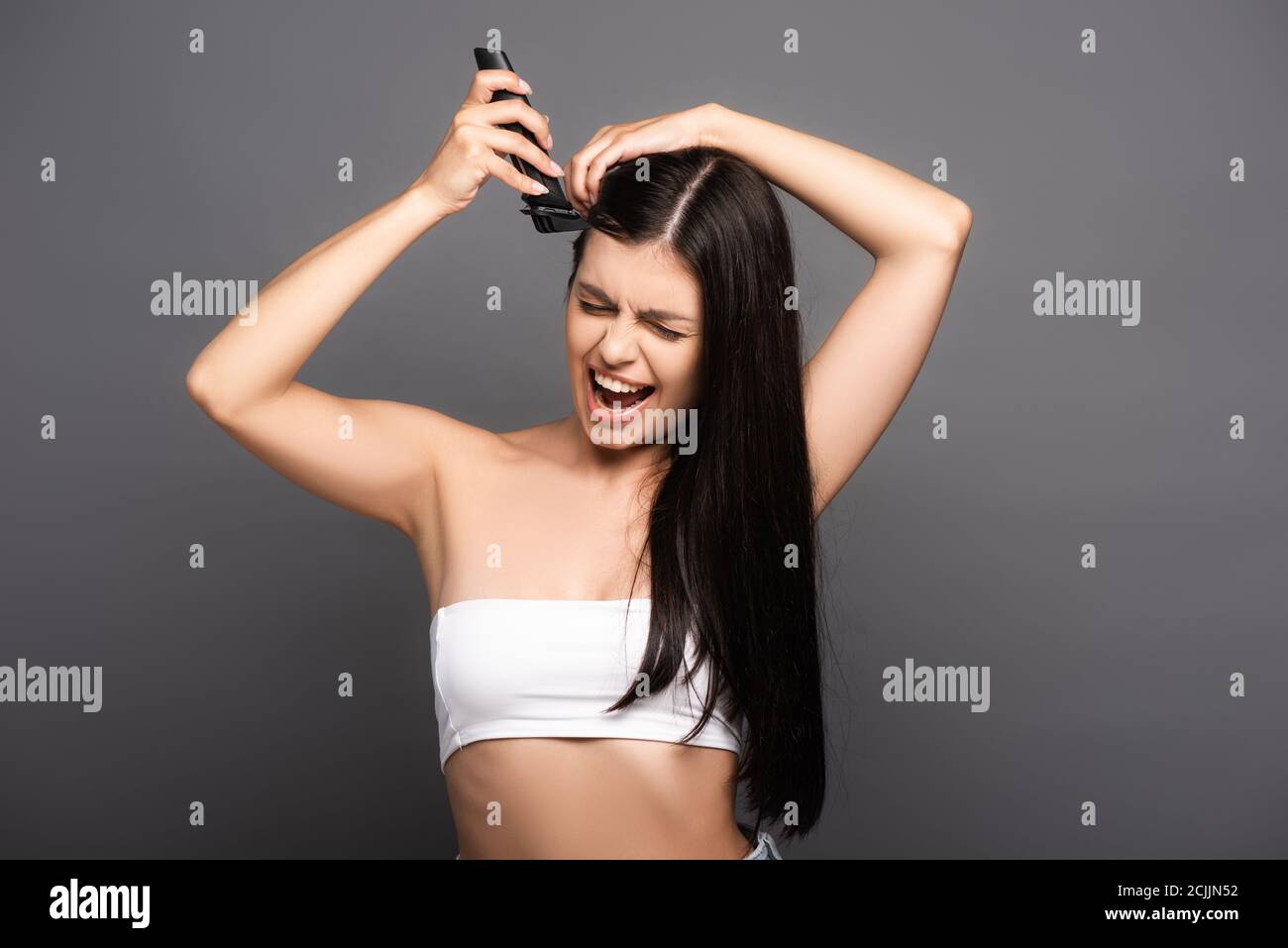 tête de rasage brunette longue cheveux femme avec rasoir électrique et  crier isolé sur le noir Photo Stock - Alamy