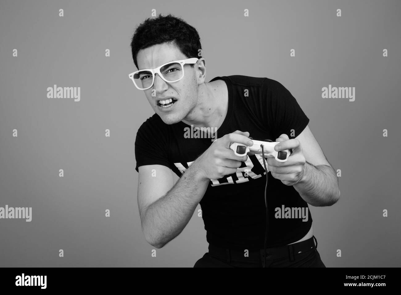 Beau jeune homme avec des lunettes nerd contre l'arrière-plan gris Banque D'Images Beau jeune homme avec des lunettes nerd contre l'arrière-plan gris Banque D'Images