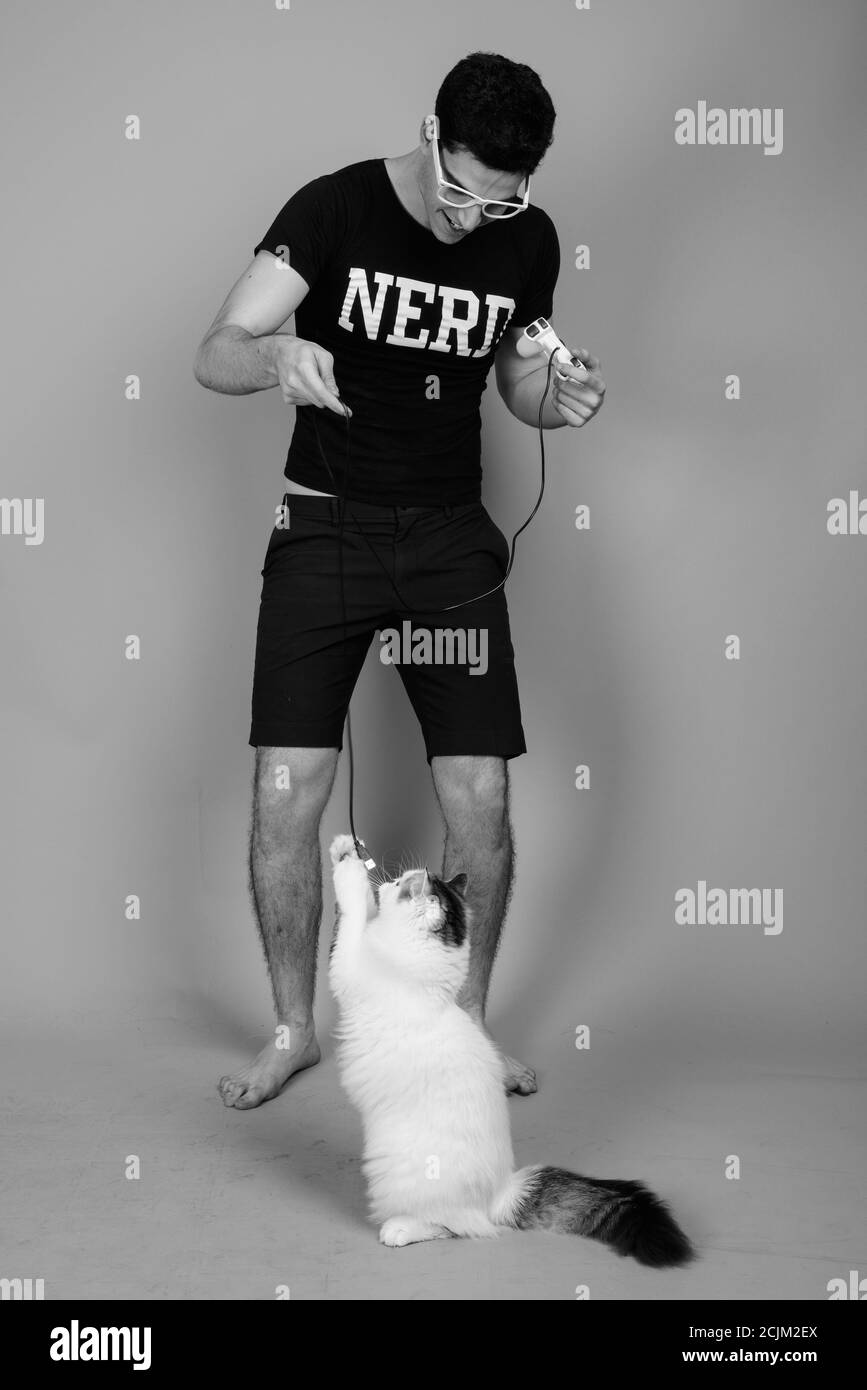 Portrait du jeune Perse nerd heureux homme jouant des jeux avec cat Banque D'Images Portrait du jeune Perse nerd heureux homme jouant des jeux avec cat Banque D'Images