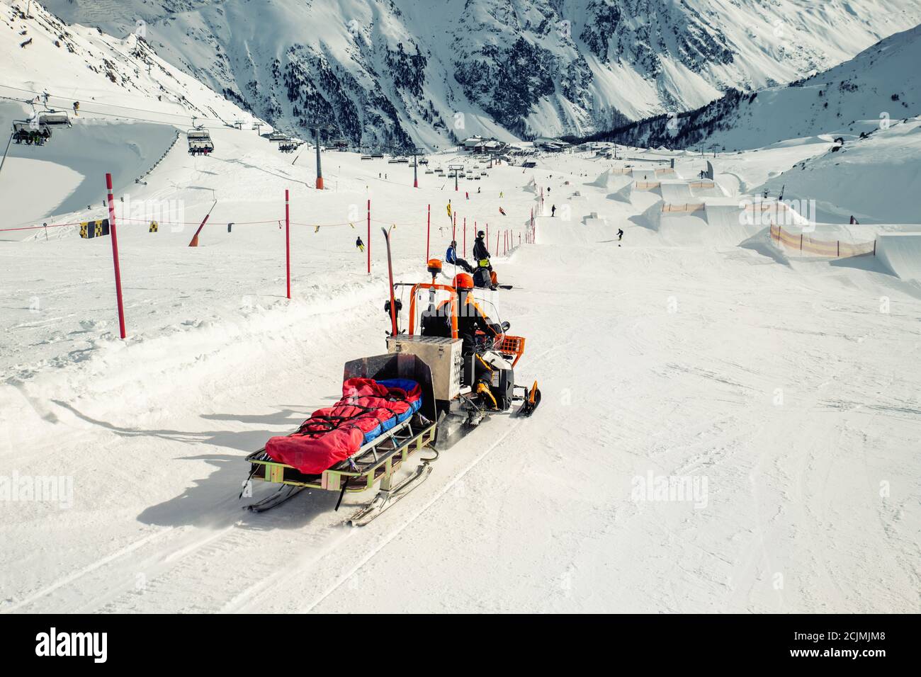 Une machine de motoneige avec traîneau et équipement roulant rapidement se dépêche le conducteur doit aider le skieur ou le snowboardeur blessé lors de l'accident station de montagne d'hiver Banque D'Images