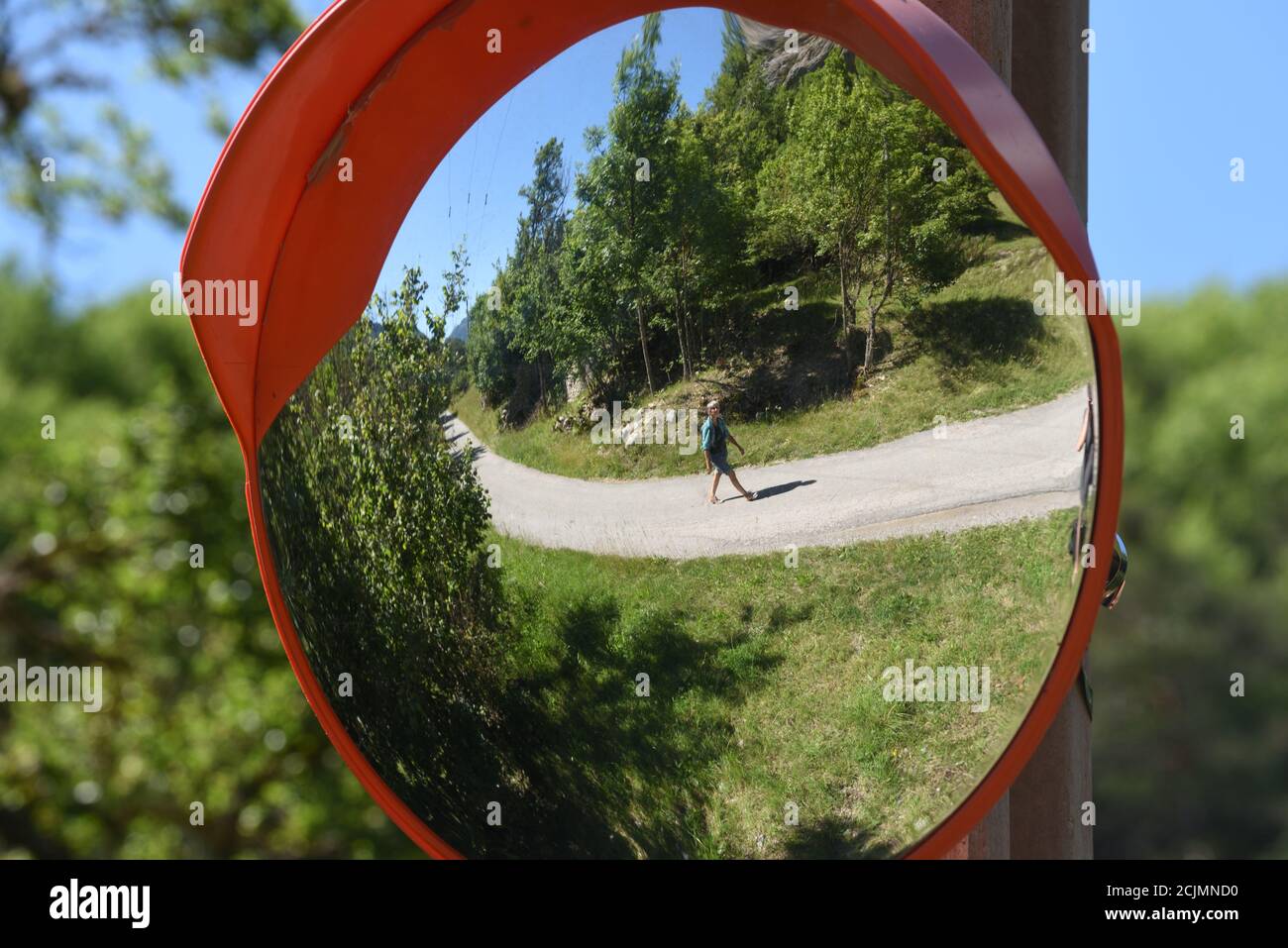 Miroir incurvé, miroir à distorsion, miroir de sécurité routière circulaire ou miroir de sécurité routière reflétant la réflexion déformée ou image miroir de la route de campagne et du paysage Banque D'Images