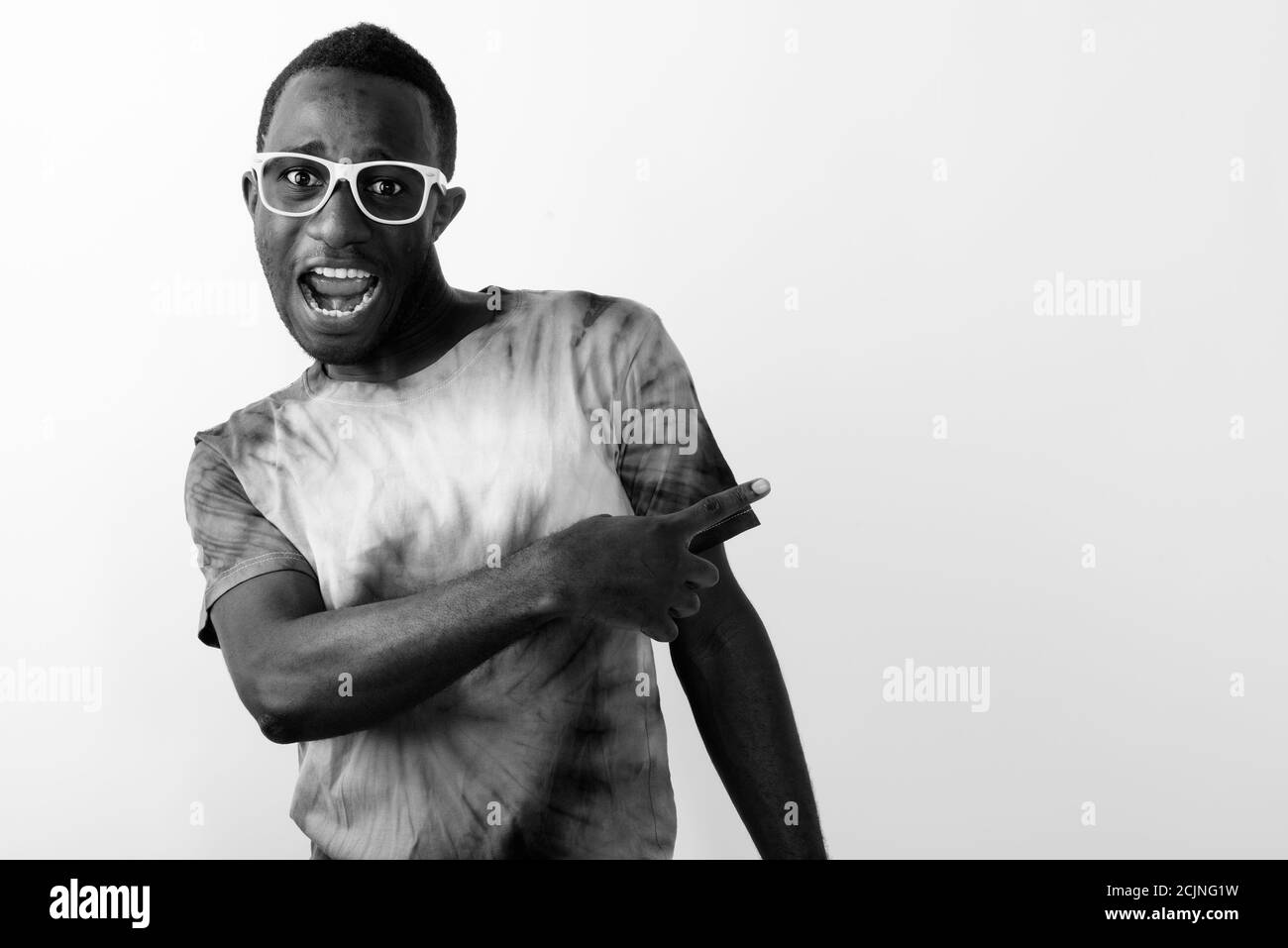 Studio de photo d'un jeune homme africain noir pointant du doigt et montrant quelque chose à ses côtés sur fond blanc Banque D'Images