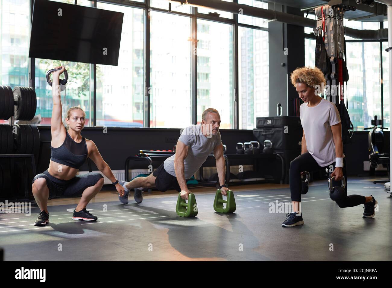Groupe de personnes en bonne santé s'entraîner avec des équipements sportifs dans moderne salle de sport Banque D'Images