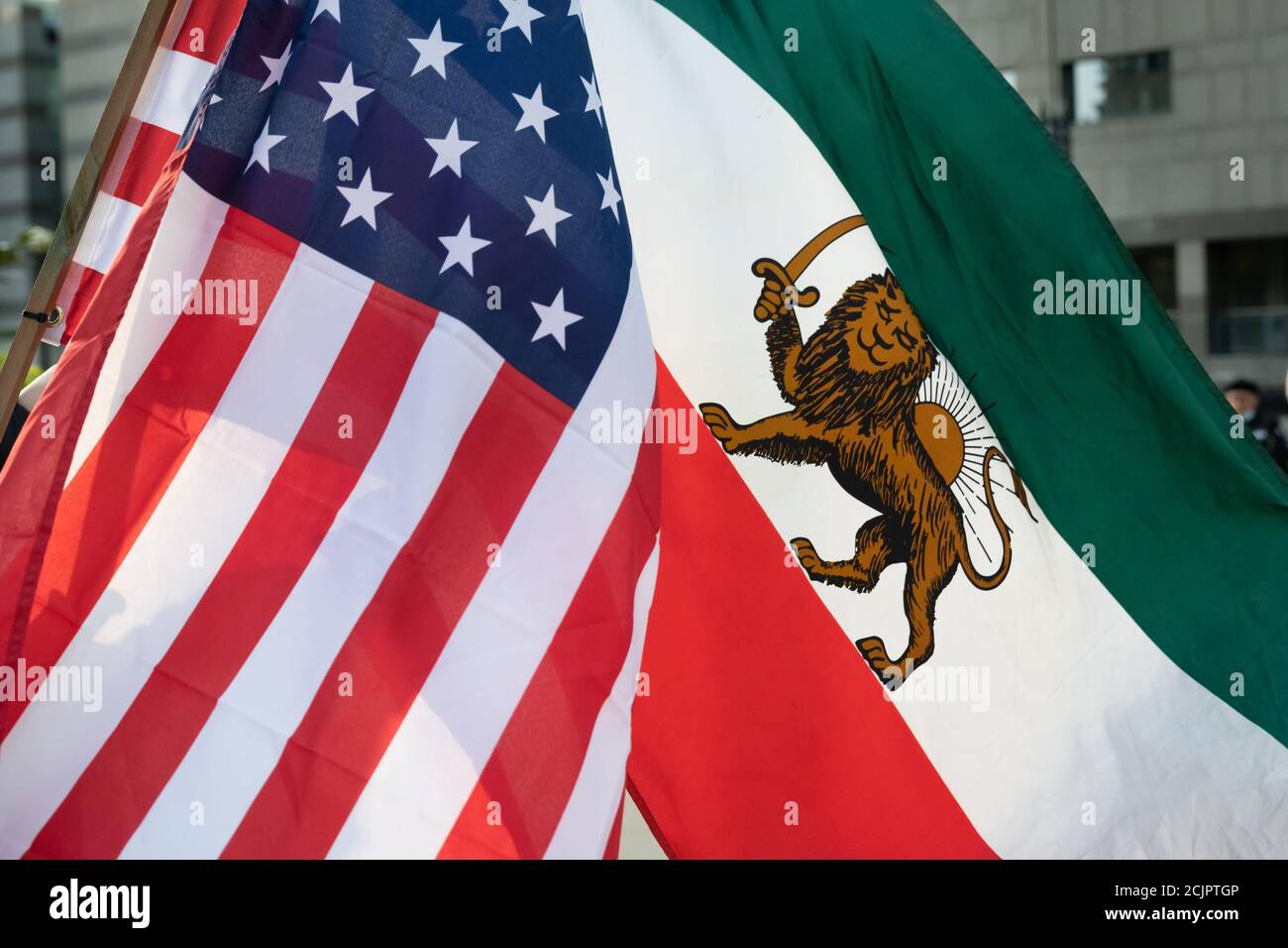 Les drapeaux iraniens du régime américain et pré-islamique volent côte à côte dans une amitié lors d'une manifestation critiquant le régime pour l'exécution de Navid Afkari. Banque D'Images