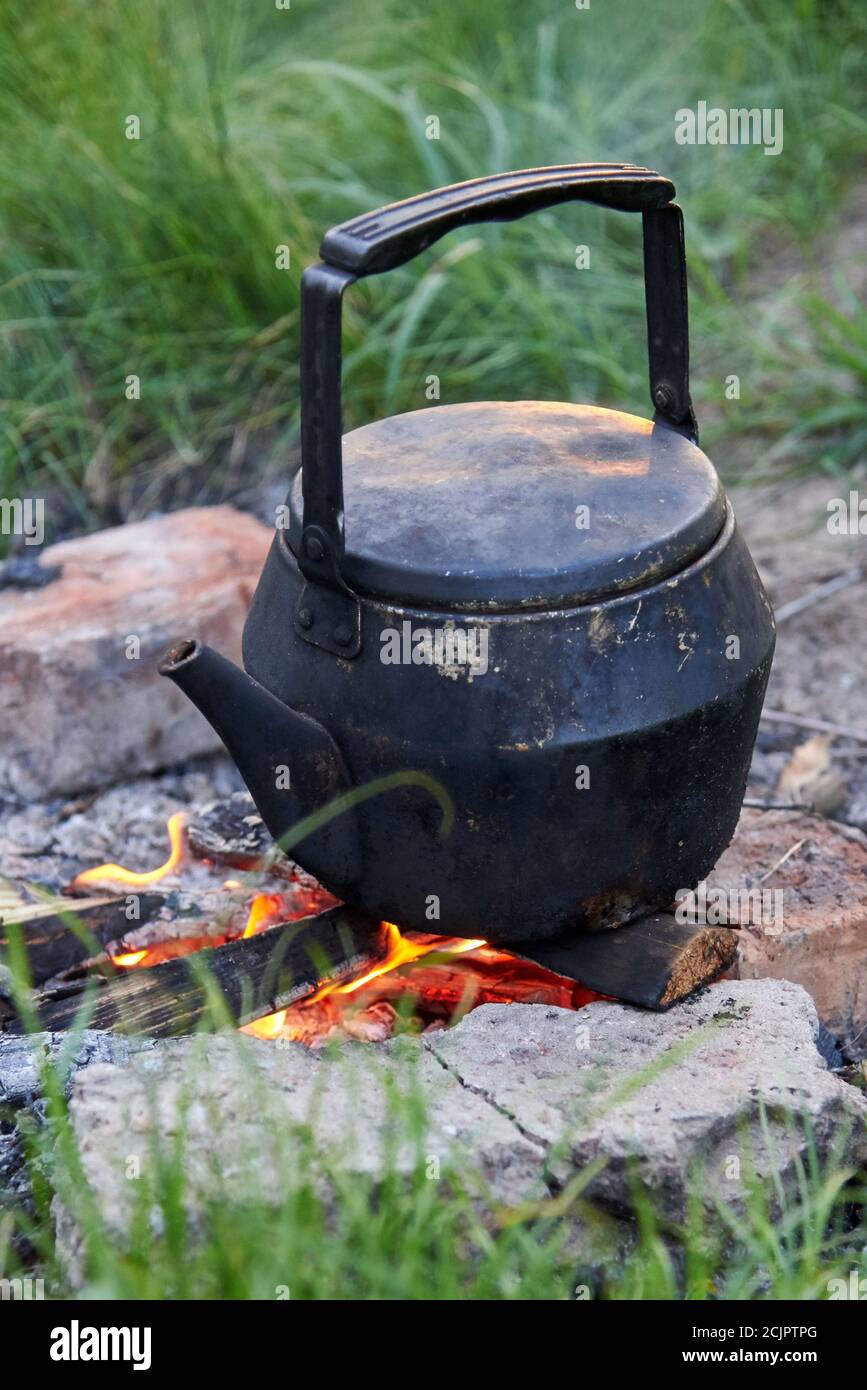 Une vieille bouilloire se tient sur un feu dans la nature, préparant le thé  lors d'un voyage de camping Photo Stock - Alamy