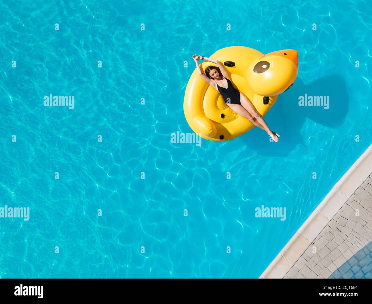 Vue de dessus photo aérienne d'un joli modèle en noir les maillots de bain profitent de la piscine en canard gonflable Banque D'Images
