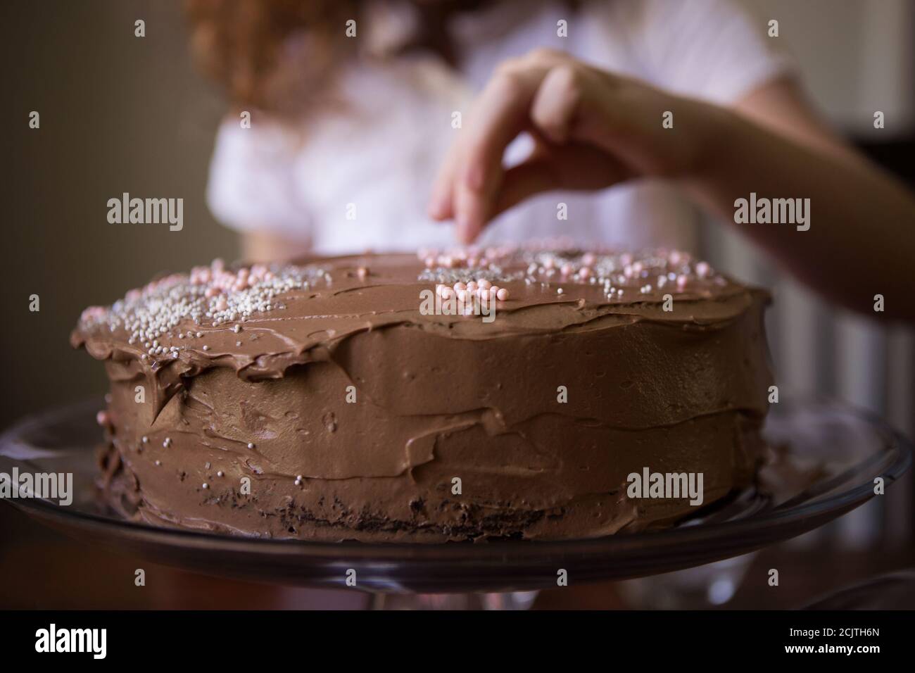 Gros plan de la main d'un enfant décorant un chocolat dépoli Gâteau d'anniversaire avec prprinkles Banque D'Images