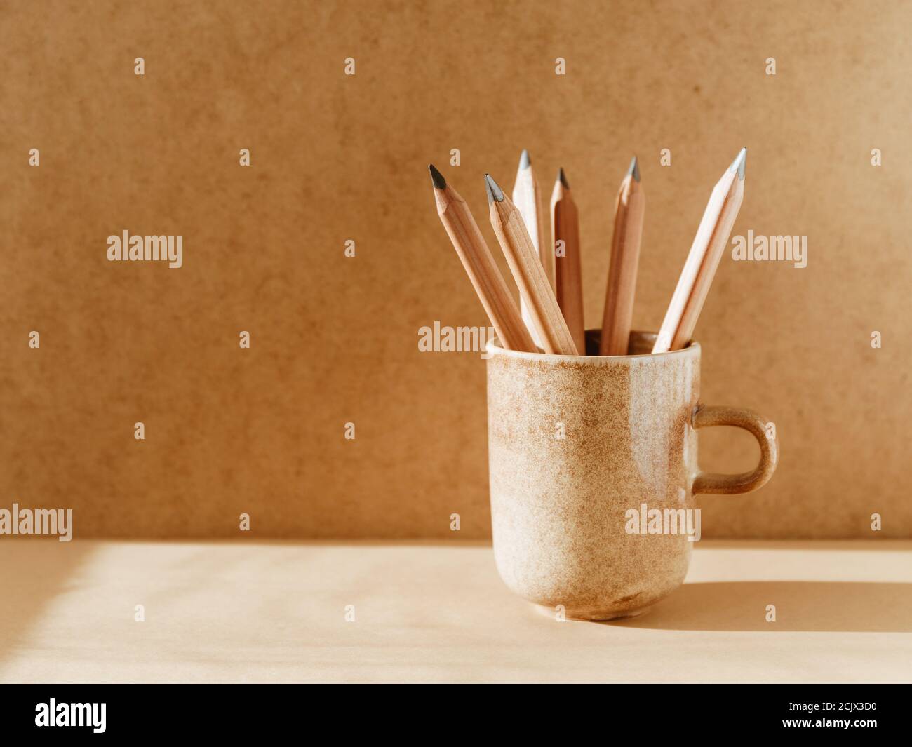 Crayons dans une tasse en céramique sur une table avec espace pour les copies. Banque D'Images