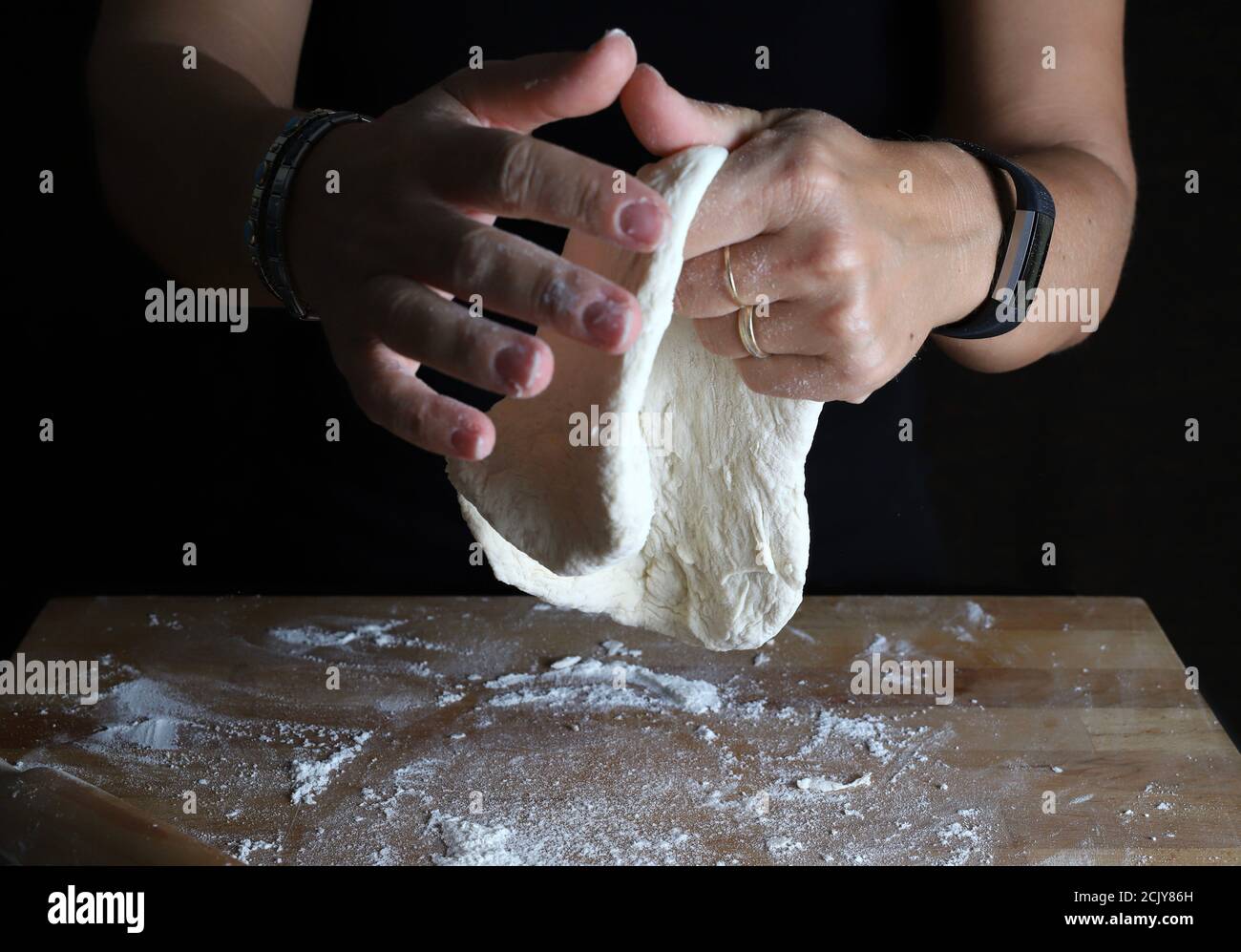 Préparation de la pâte maison. La femme pétrit la pâte fraîche pour faire du pain ou de la pizza sur une table farinée. Banque D'Images