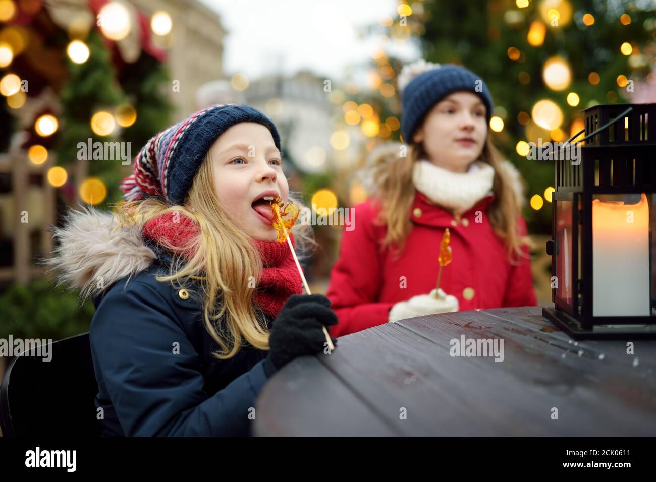 Deux adorables sœurs ayant en forme de coq sur les sucettes de Noël traditionnel à Riga, Lettonie. Les enfants bénéficiant des bonbons, confiseries et pain d'épices Banque D'Images
