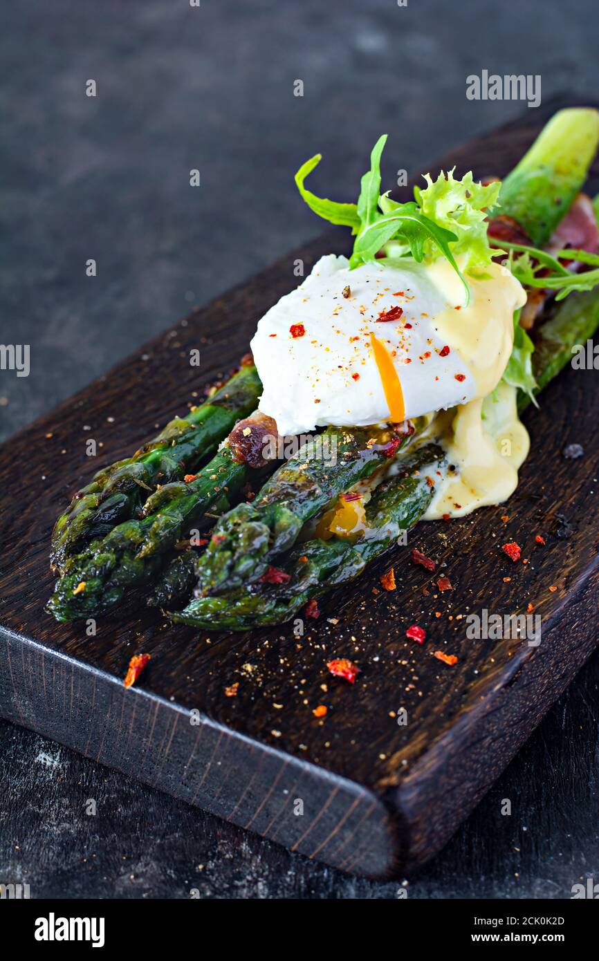 Petit-déjeuner d'asperges cuites aux épices avec bacon, œuf poché et salade croustillante. Accompagnement pour le déjeuner et le dîner. Banque D'Images