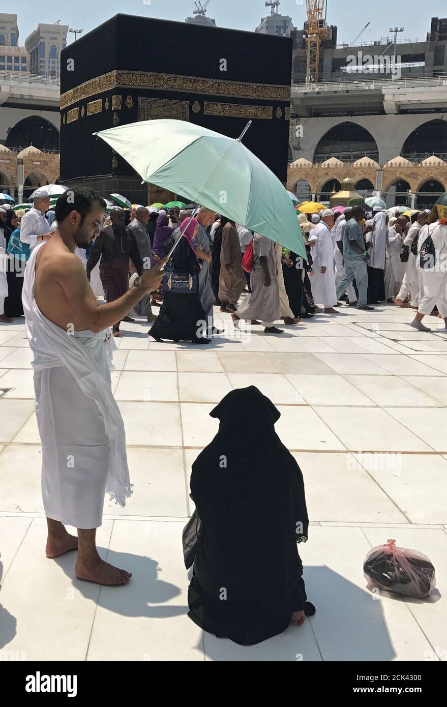 Un pèlerin musulman utilise un parapluie pour protéger sa femme du soleil  pendant qu'elle priait à la Grande mosquée à la fin du pèlerinage annuel de  Haj à la Mecque, Arabie Saoudite