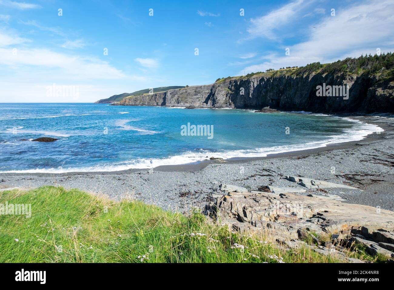 Océan bleu vif avec une petite vague blanche qui rencontre la plage de galets vide en été. Banque D'Images