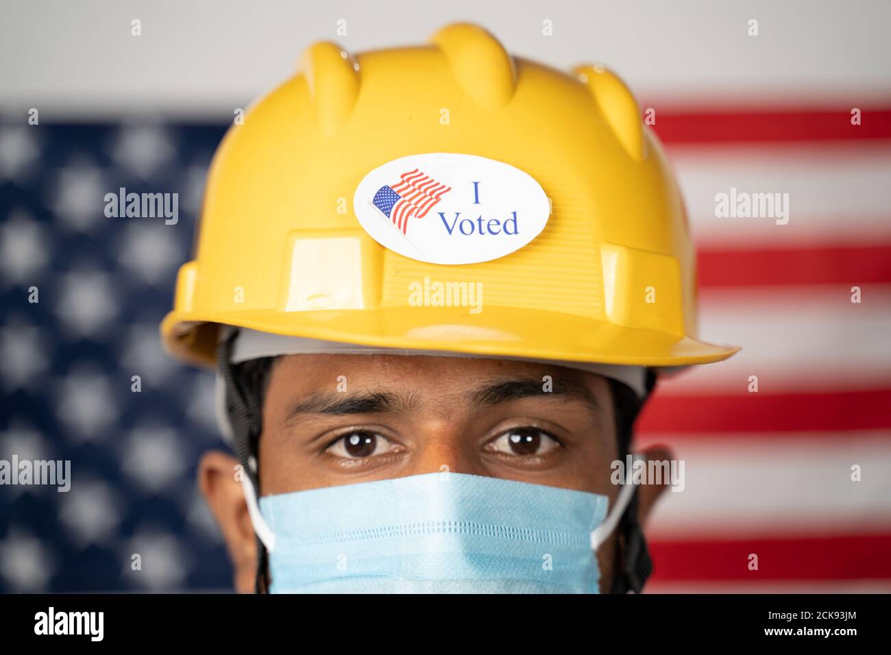 Gros plan de j'ai voté autocollant sur le casque de travailleur avec le drapeau américain comme arrière-plan - concept des élections et vote aux États-Unis. Banque D'Images