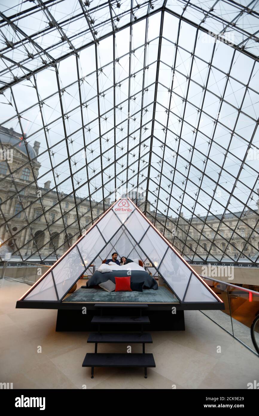 Les employés d'Airbnb posent sur un lit sous la Pyramide de verre lors  d'une répétition au musée du Louvre à Paris, France, le 12 mars 2019.  Airbnb et le musée du Louvre