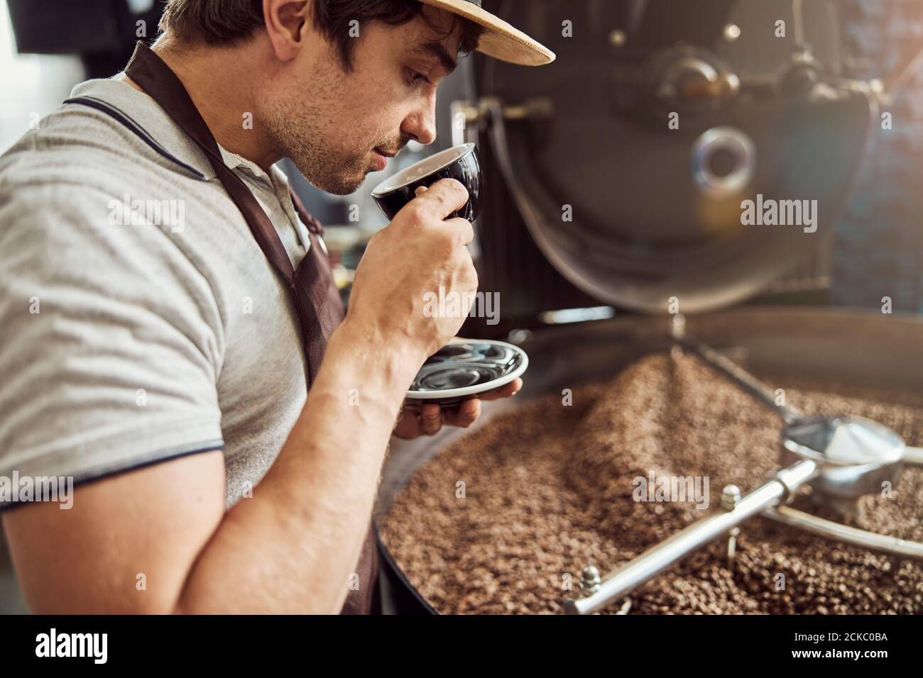 Beau homme buvant du café près de la machine à rôtir Banque D'Images