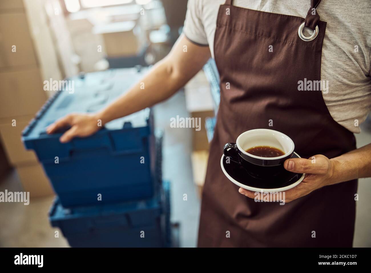 Main de travail masculine tenant une tasse de café noire Banque D'Images