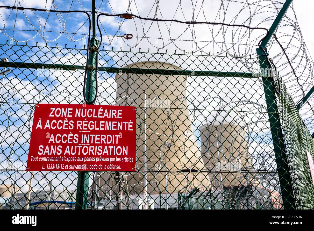 Vue rapprochée d'un panneau d'avertissement sur la clôture de sécurité avec fil barbelé d'une centrale nucléaire en France. Banque D'Images
