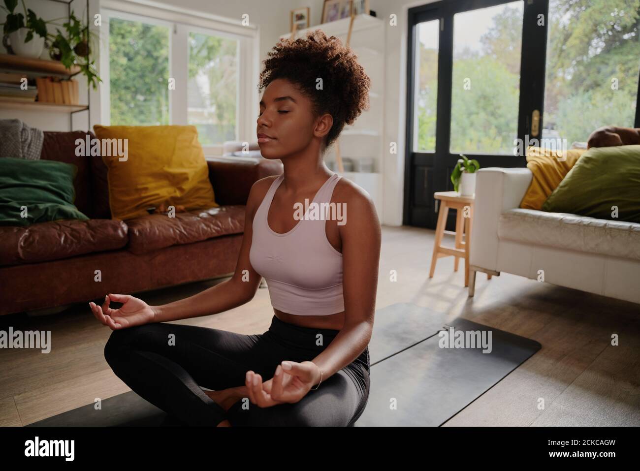 Jeune femme noire faisant du yoga à la maison dans la position du lotus Banque D'Images