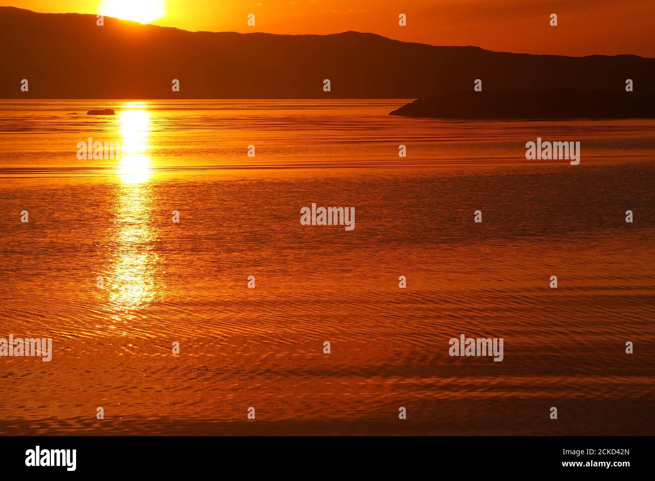 Coucher de soleil sur la baie de Carsaig, Tayvallich, Argyll, Écosse, yacht en silhouette avec l'île du Jura de l'autre côté du son du Jura Banque D'Images