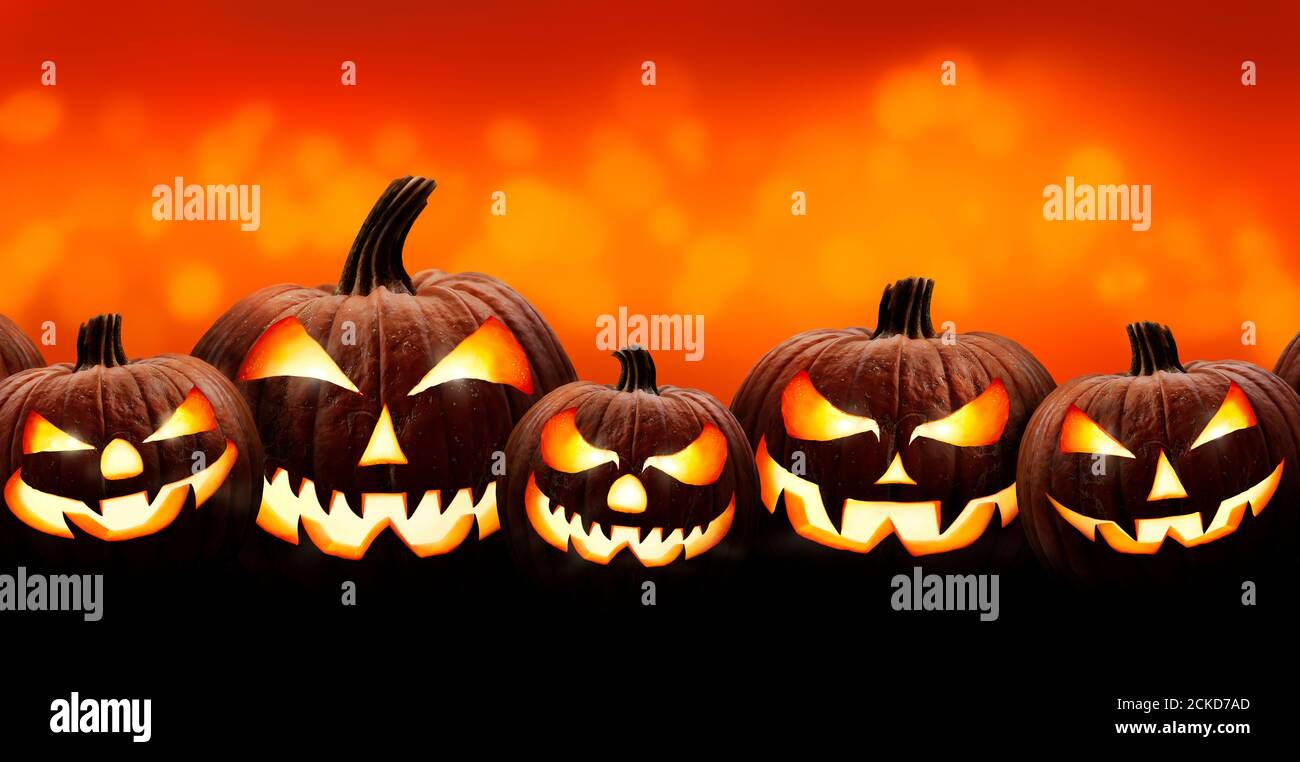 Cinq lanternes d'halloween, Jack O, avec des yeux et des visages effrayants et mal isolés contre un fond orange et jaune éclairé. Banque D'Images