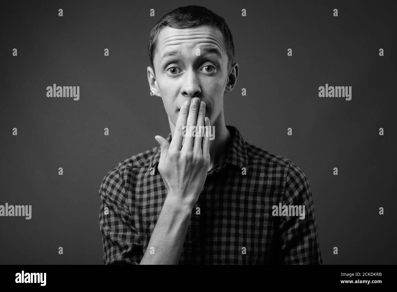 Portrait de jeune homme hipster contre l'arrière-plan gris Banque D'Images