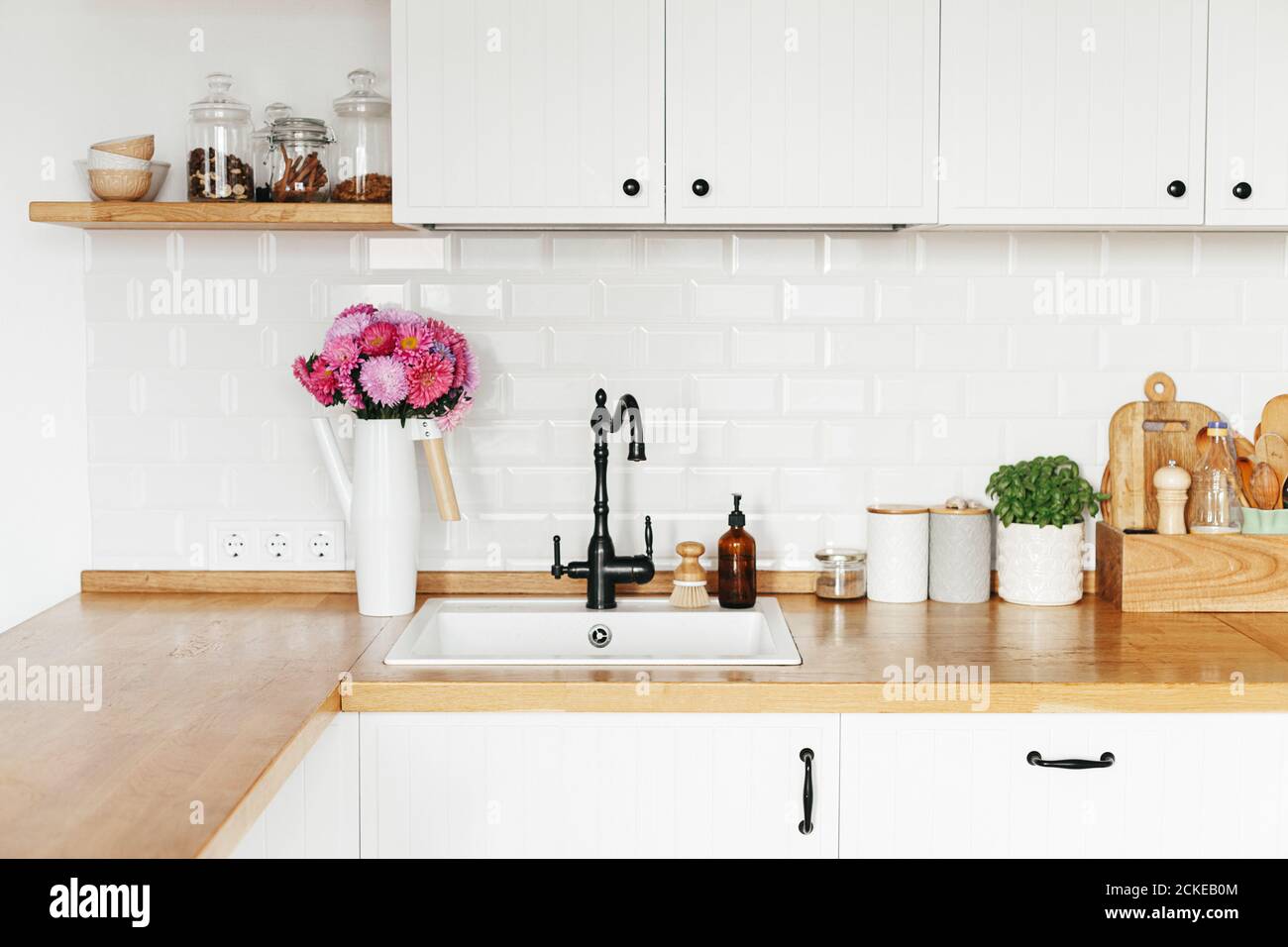 Vue sur blanc propre cuisine moderne simple dans le style scandinave, détails de cuisine, table en bois, aster Michaelmas bouquet de Marguerite dans vase sur la table Banque D'Images