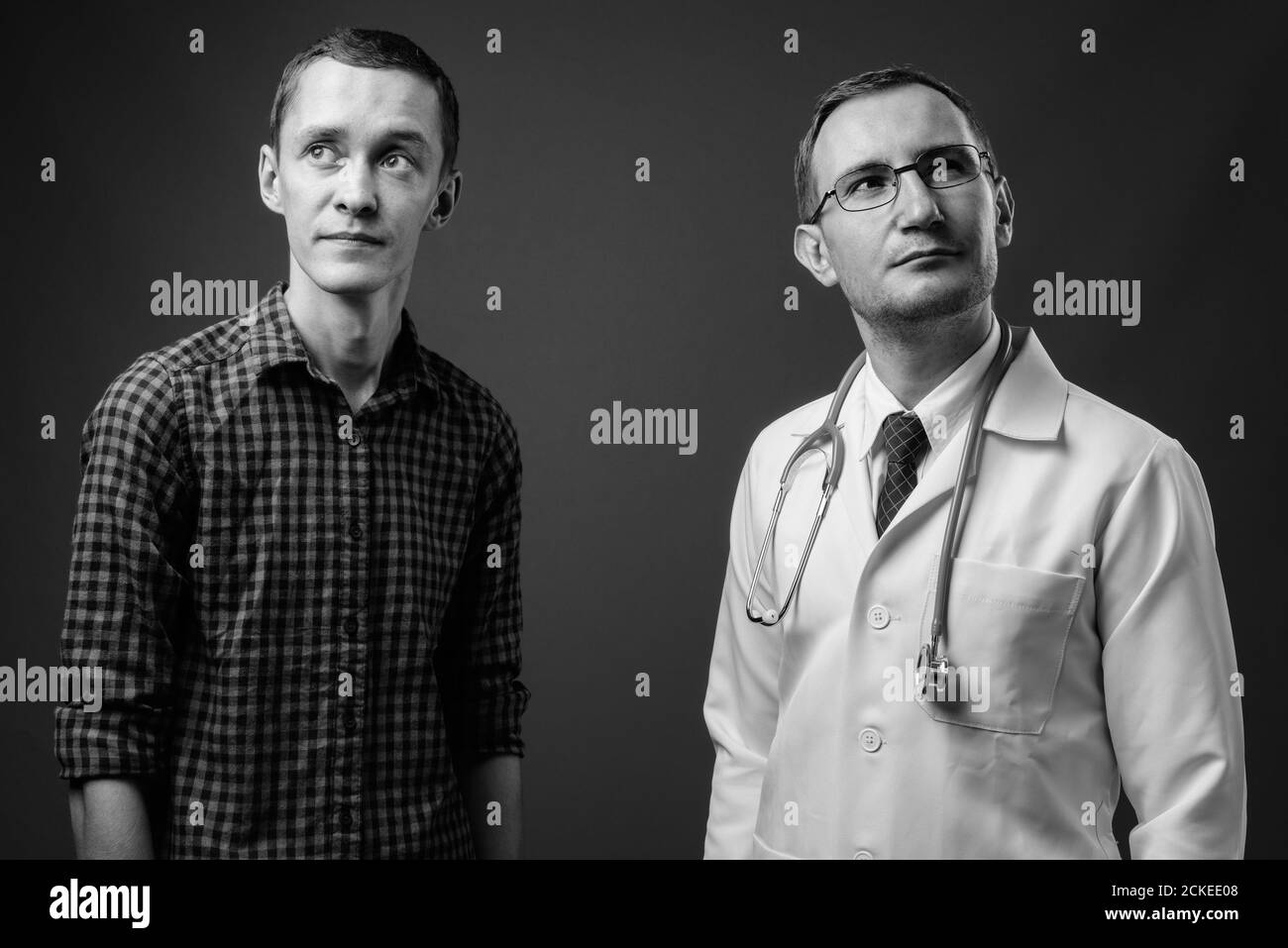 Homme médecin et jeune homme patient sur fond gris Banque D'Images