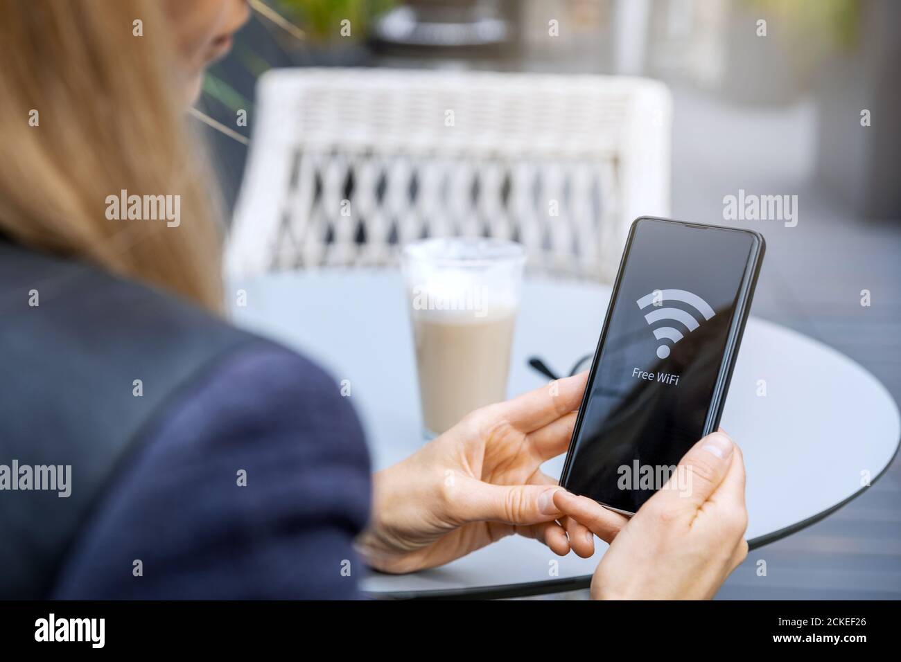 espace wi-fi gratuit - une femme connecte le téléphone au public réseau sans fil au café Banque D'Images