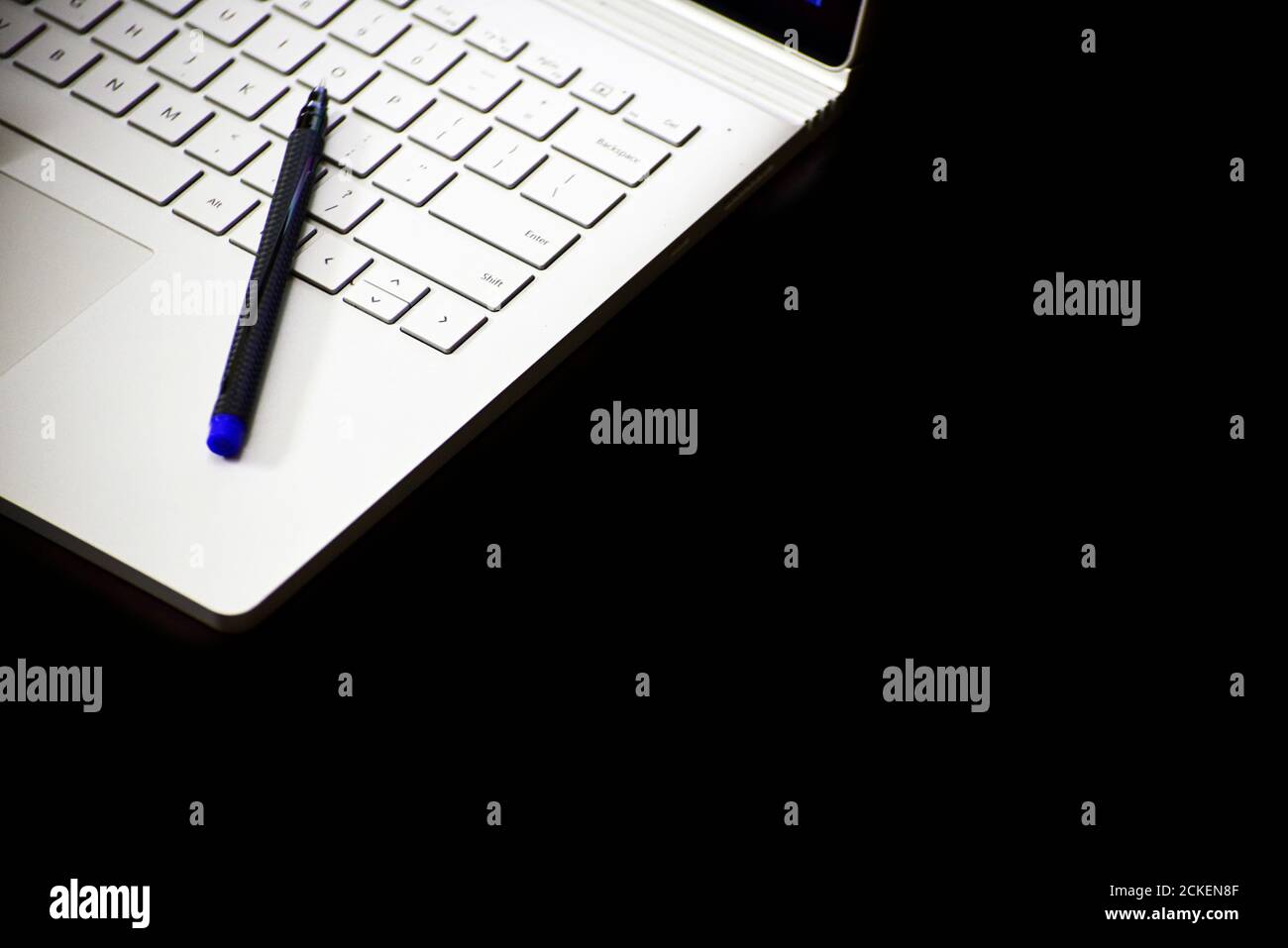 gros plan d'un stylet reposant sur le clavier de l'ordinateur portable arrière-plan noir Banque D'Images