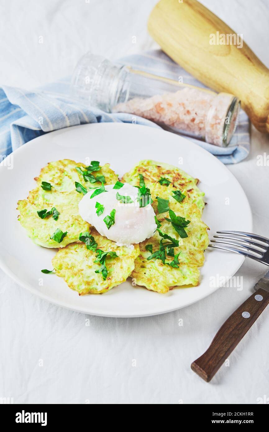 Crêpes de courgettes de légumes avec œuf poché sur une assiette blanche Banque D'Images