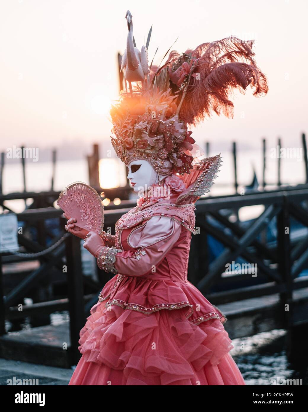 Déguisement/masque traditionnel de carnaval posé tôt le matin au bord de l'eau pendant un lever de soleil au carnaval annuel à Venise, Italie Banque D'Images Déguisement/masque traditionnel de carnaval posé tôt le matin au bord de l'eau pendant un lever de soleil au carnaval annuel à Venise, Italie Banque D'Images