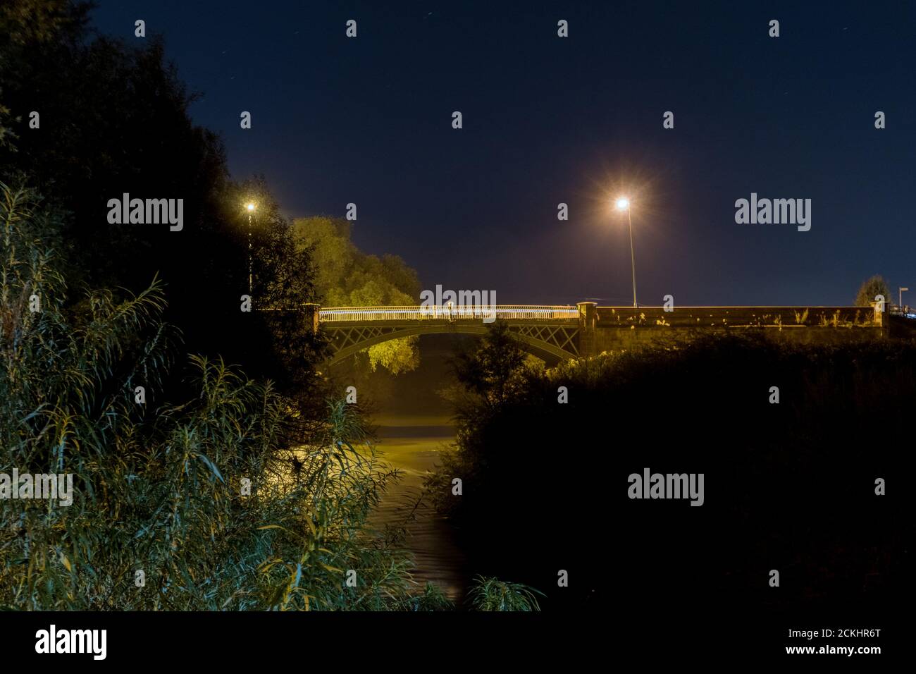 Une scène nocturne de lumières de rue reflétées dans une rivière. Avec un pont en arrière-plan. Banque D'Images