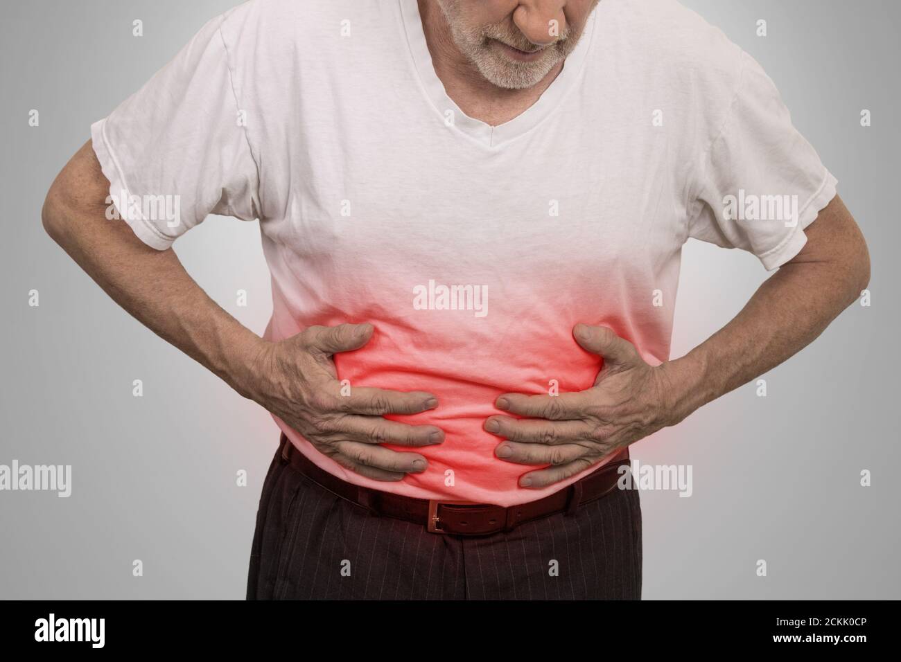 Maux d'estomac, homme plaçant les mains sur l'abdomen isolé sur fond de mur gris Banque D'Images