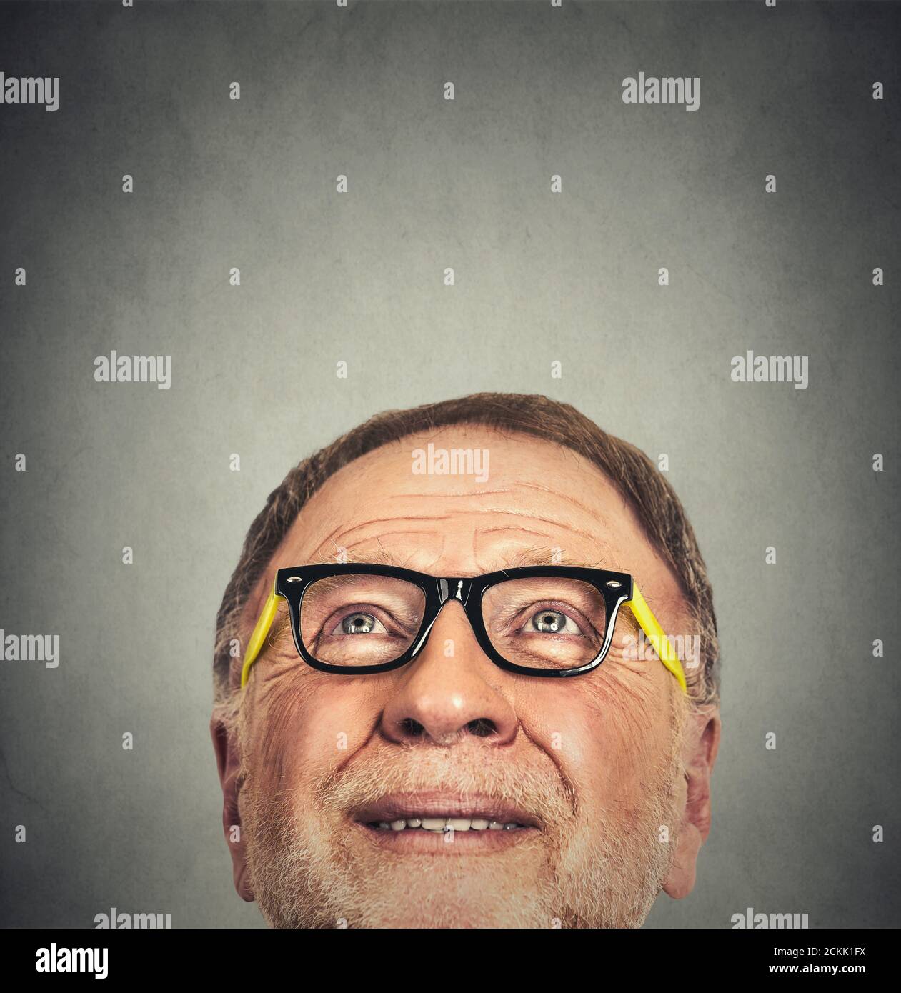 Gros plan Portrait de l'ancien homme avec des lunettes de vue isolées sur fond de mur gris avec espace de copie Banque D'Images