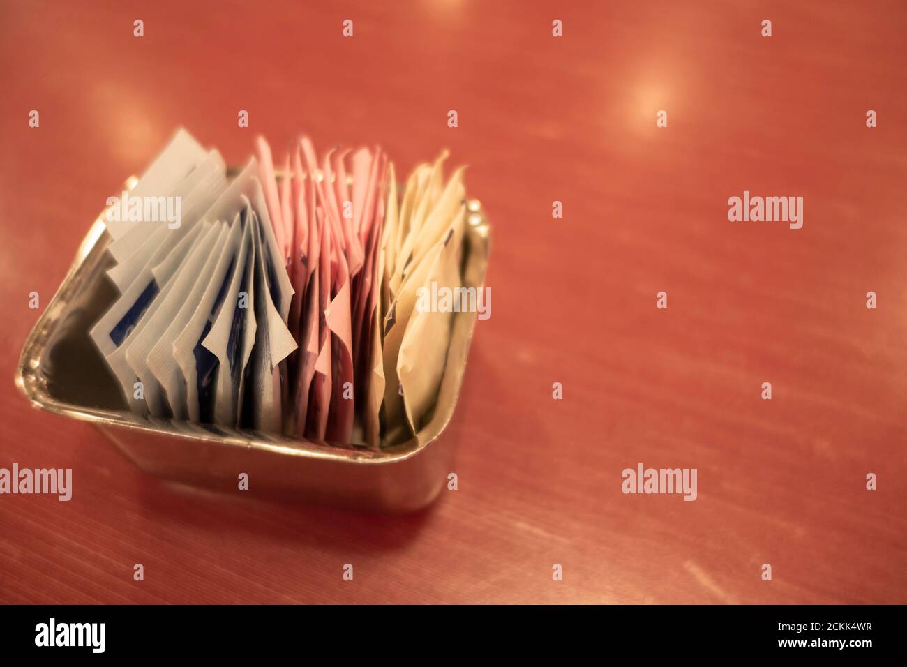 Un récipient de sachets d'édulcorant et de sucre sur une table. Banque D'Images