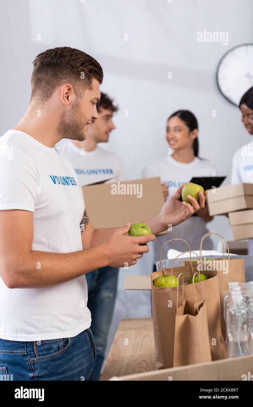 Objectif sélectif des bénévoles qui tiennent des pommes près des sacs de papier à l'intérieur centre de bienfaisance Banque D'Images