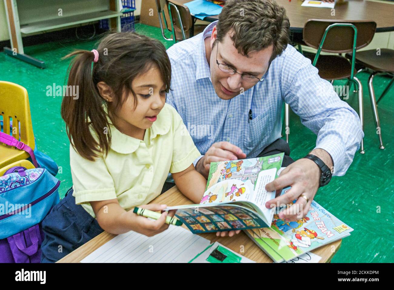 Miami Florida,Frederick Douglass Elementary School,quartier à faible revenu,hispanique étudiant fille cabinet d'avocats employé donnant livre don homme de classe Banque D'Images